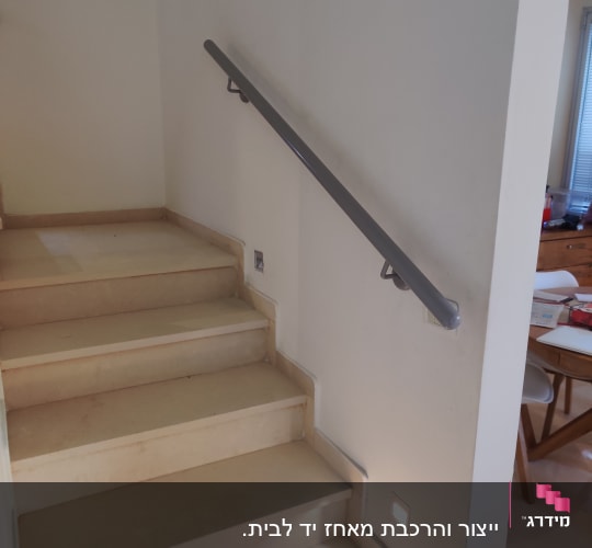 מעקה מתכת אפור על קיר מדרגות פנימי